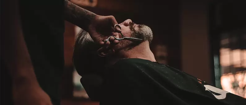 A barber trims the beardline of a customer at a Northern Colorado barbershop