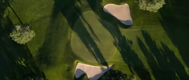 An aerial view of a circular golf green with two sand traps in East Dallas Fort Worth