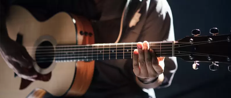 The hands of a guitarist play an acoustic guitar in a Knoxville music venue