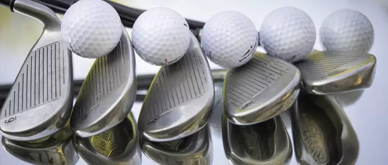Five golf balls lie atop five chipping wedges at a Northeast Florida golf course