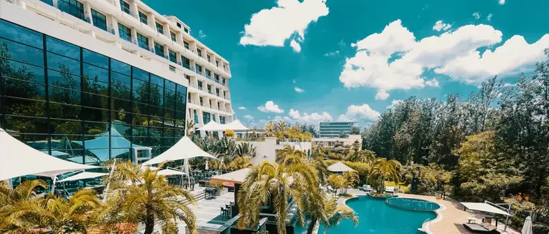 The glass façade of a Katy, Texas hotel overlooks palms tree and pool