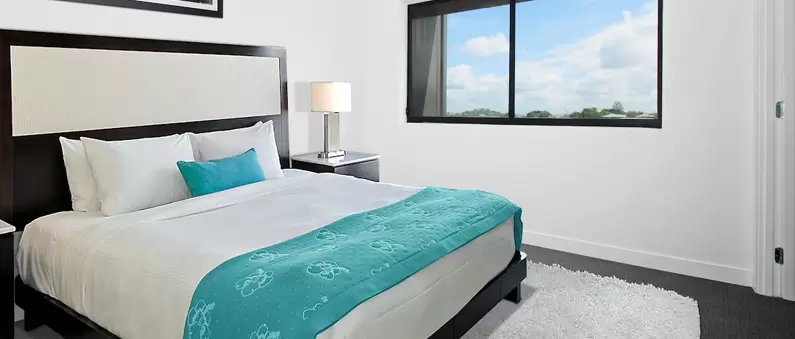A king-size bed covered with a white comforter in a Lubbock hotel room