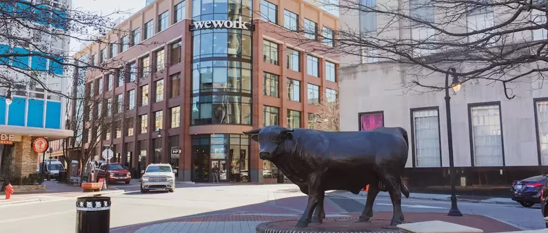 A bronze bull statue stands in front of the We Work headquarters in Durham, NC