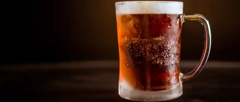 A heavy mug of dark beer with a one inch head in a Katy bar