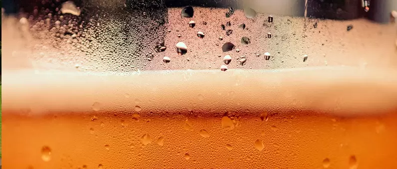 A very close up image of a full beer glass in a East DFW brewery