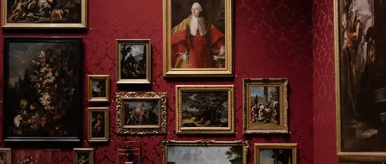 Classic paintings hang on a red wall in a museum like those found in East Forth Worth
