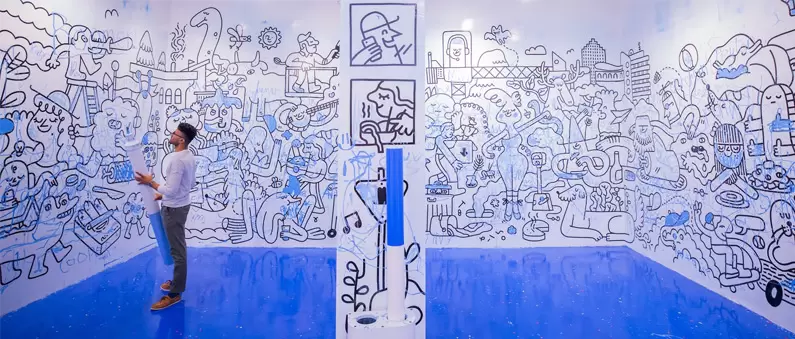 A man uses a blue marker to color cartoons on the wall at the Color Museum in Northwest Houston